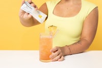 a woman is pouring a drink into a glass